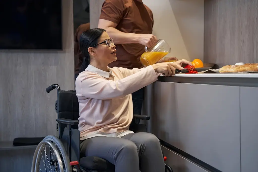 A woman in a wheelchair prepares food in the kitchen, demonstrating the ability to perform household tasks