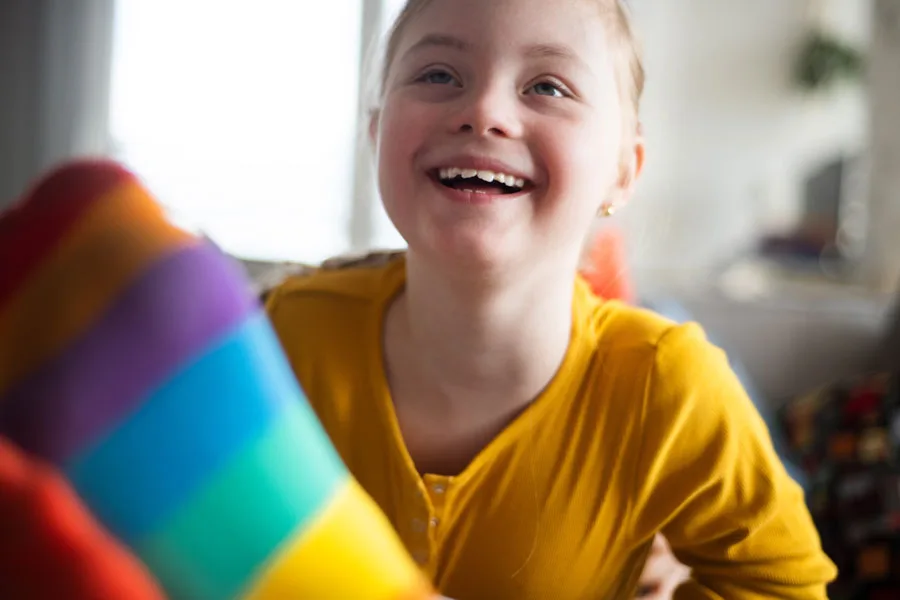 A smiling young girl with Down syndrome, representing Positive Behaviour Support and joyful care.