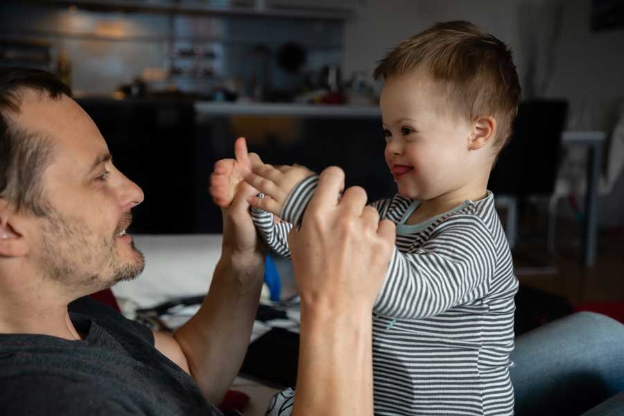 A father and his young child with Down syndrome engaging in playful interaction, highlighting Positive Behaviour Support.