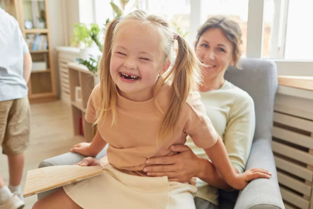 A child with Down syndrome enjoys a playful moment with their caregiver, facilitated by NDIS Support Services Melbourne.