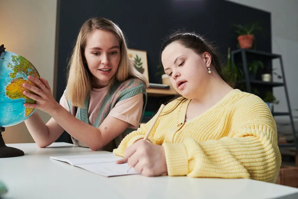 A teacher from NDIS Support Services Melbourne helps a student explore geography with the aid of a globe.