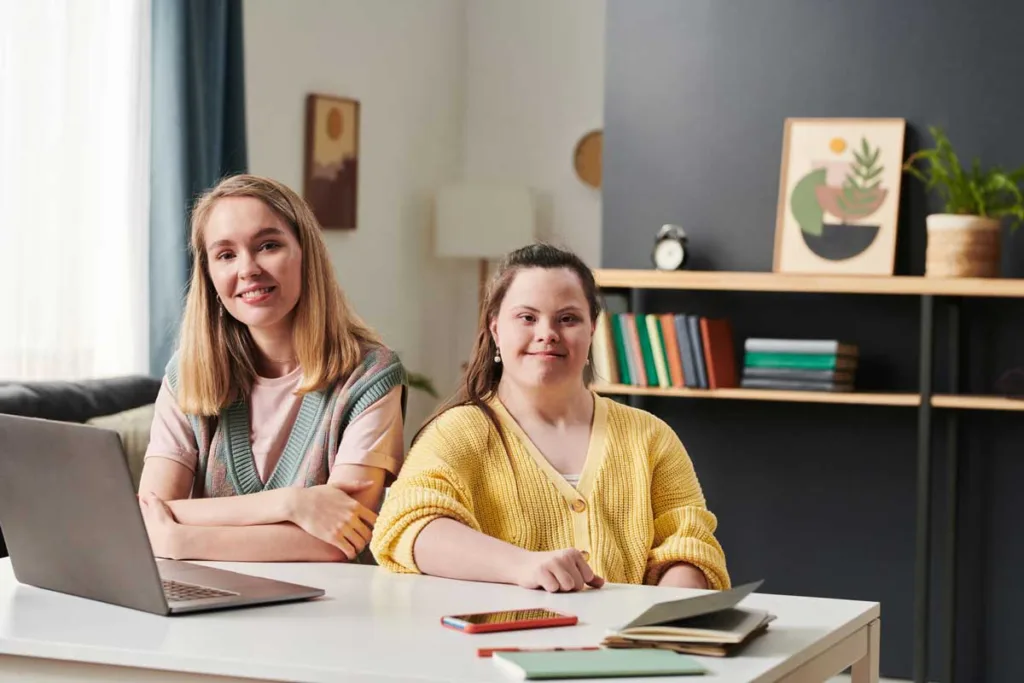 A supportive tutor providing one-on-one ndis support coordination to a focused student with Down syndrome at a well-organized study space.