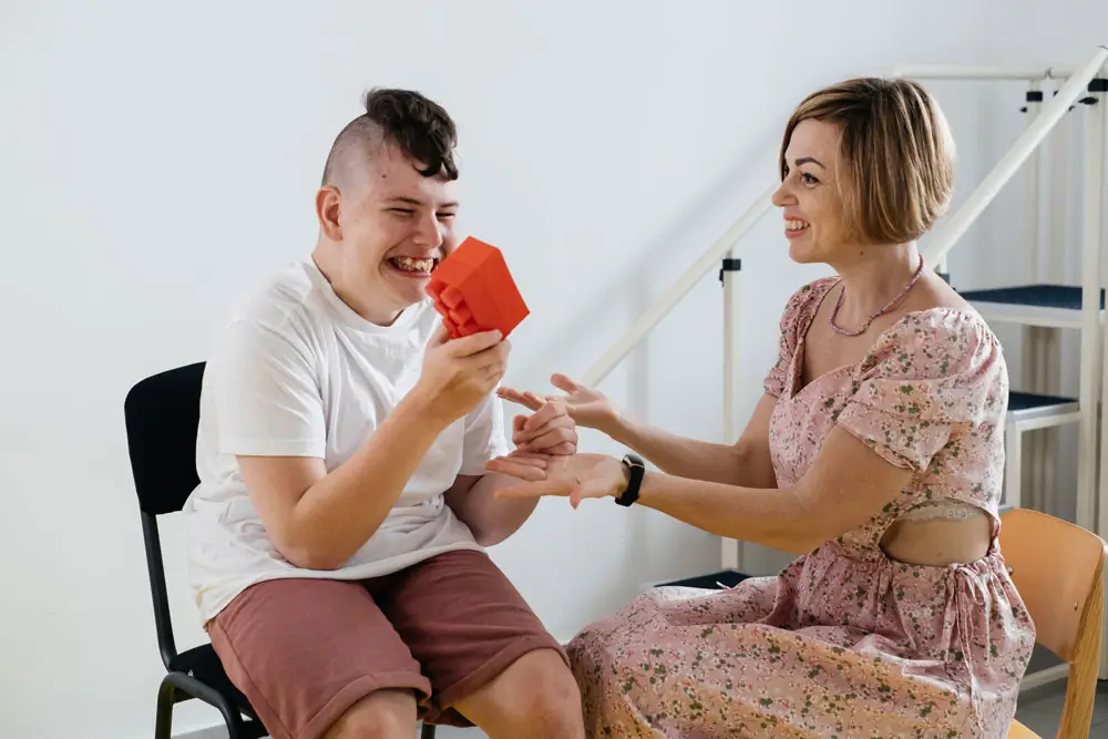 A therapist from NDIS Support Services Melbourne engages a young man with building blocks during a session.