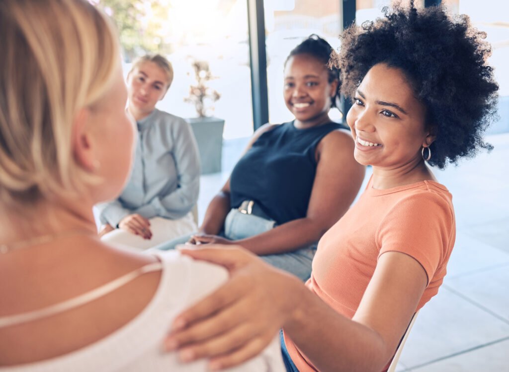 A group therapy session for domestic violence counselling, with a woman offering comfort to another, highlighting the importance of community and support.