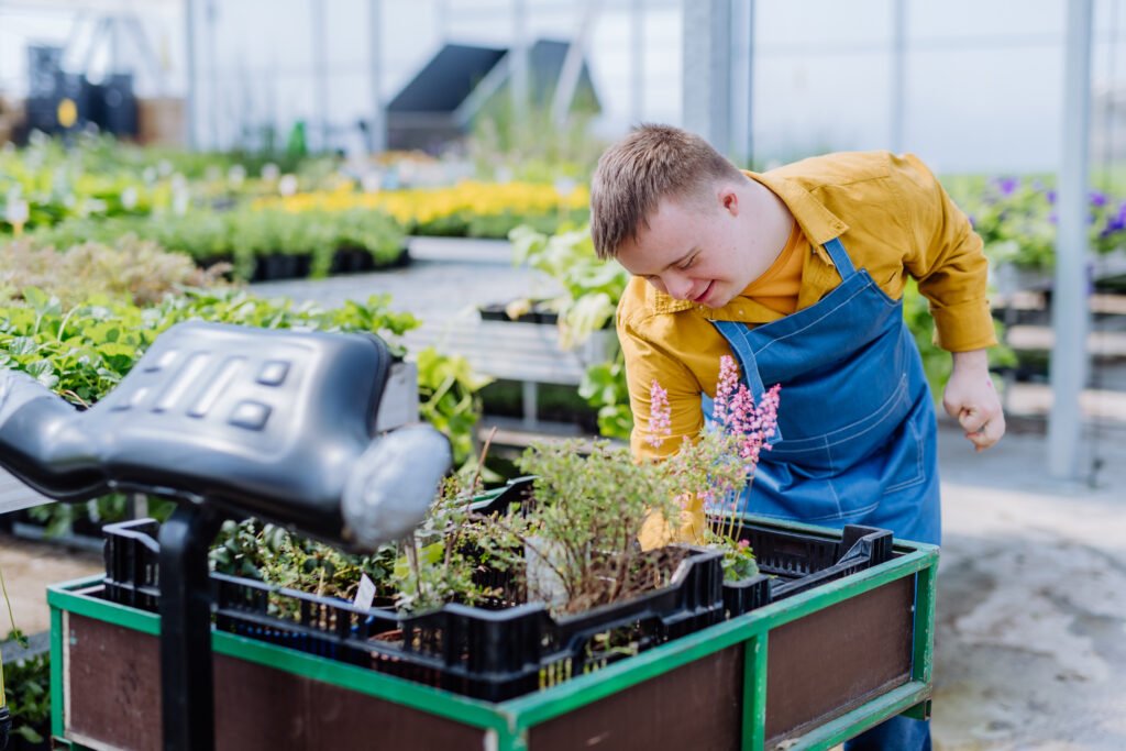 A person with Down syndrome working in the garden, demonstrating the cultivation of independent living skills through outdoor activities and gardening tasks.