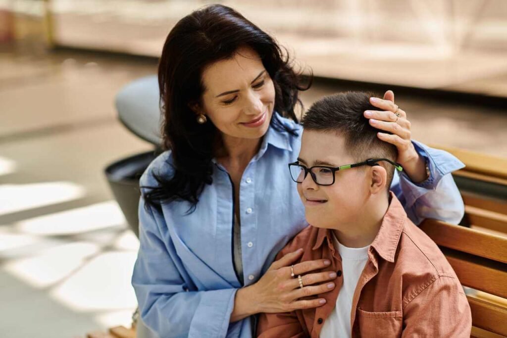 A mother and her son, who has Down syndrome, enjoying a tender moment on a bench. The mother gently touches her son's head, illustrating the compassionate support often facilitated by NDIS support coordinators for families and individuals with disabilities.