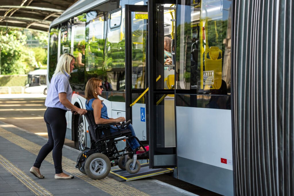 Woman in a wheelchair being assisted onto an accessible bus, showcasing transport support services available for people with disabilities in Australia.