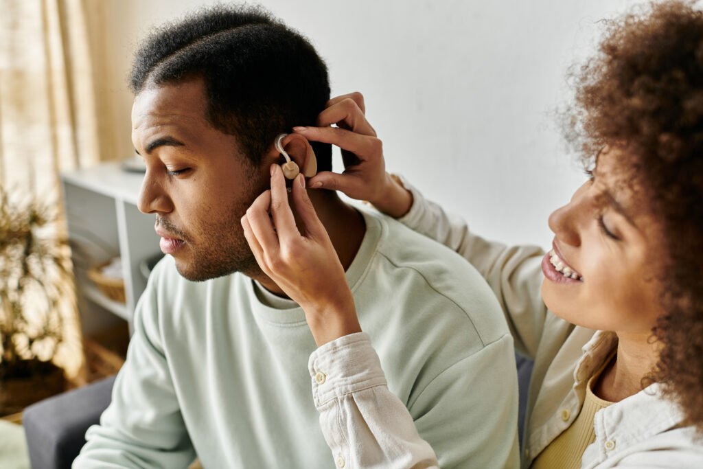 Woman helping a man with hearing aids, highlighting assistive technology as one of the key disability services available in Australia.