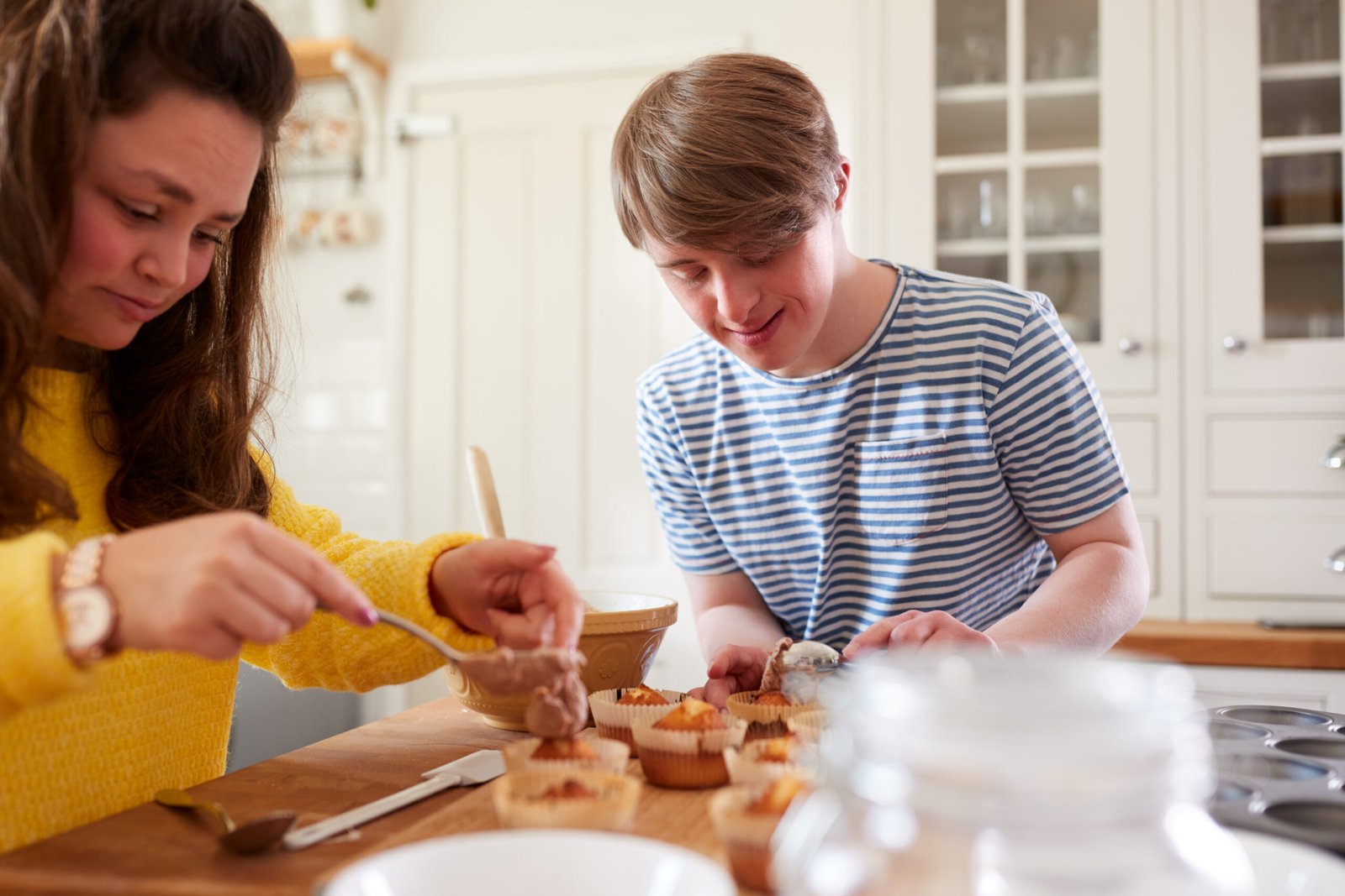 A person with Down syndrome helping with baking, showcasing the development of independent living skills through activities like cooking and kitchen tasks.