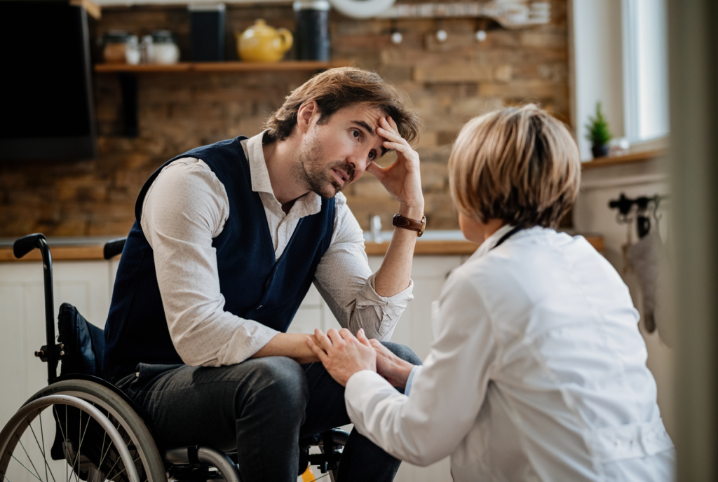 A man in a wheelchair is comforted by a healthcare professional, illustrating the support offered by NDIS service providers.